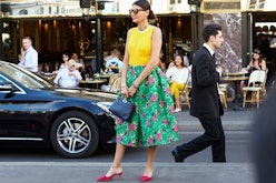 A lady standing in a green floral dress on a street