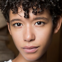 A close-up portrait of a curly-haired woman wearing some of the buzzy beauty buys