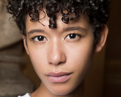 A close-up portrait of a curly-haired woman wearing some of the buzzy beauty buys