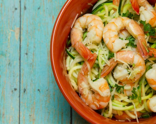 A red bowl with shrimp salad keto recipe on a green wooden surface