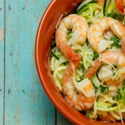 A red bowl with  shrimp salad keto recipe on a green wooden surface