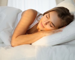 A blonde woman sleeping on a pillow in her bed