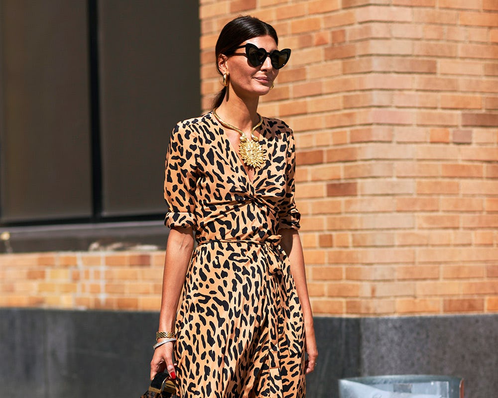 A woman in a leopard print dress, tied-up hair and heart-shaped sunglasses 