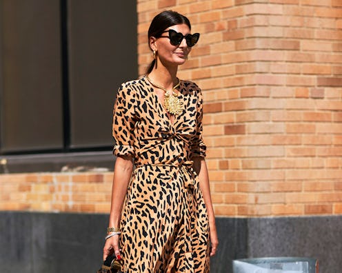 A woman in a leopard print dress, tied-up hair and heart-shaped sunglasses 