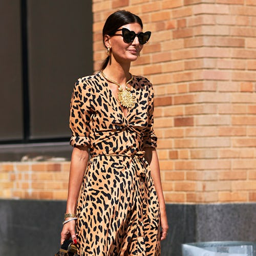 A woman in a leopard print dress, tied-up hair and heart-shaped sunglasses 