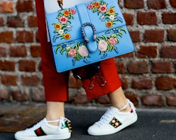 A woman with a blue floral bag, red trousers, and white sneakers from Fourth Of July sales
