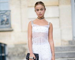 Lady Amelia Windsor in a white dress, with her hair in a bun, holding a black Dior bag
