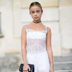 Lady Amelia Windsor in a white dress, with her hair in a bun, holding a black Dior bag