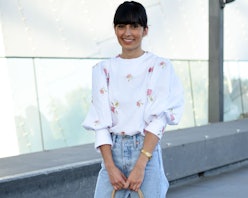 A woman in a white floral top and light denim jeans