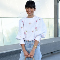 A woman in a white floral top and light denim jeans