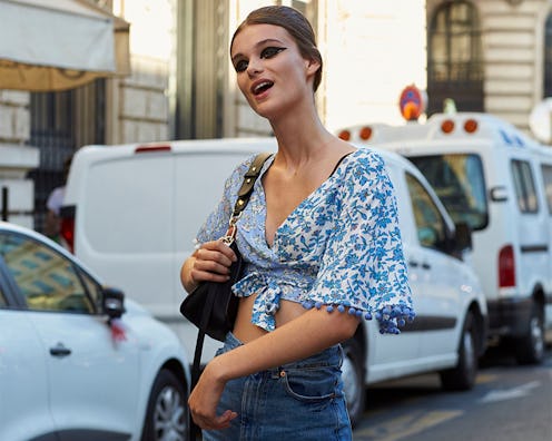 A woman in a feminine outfit combination; white-blue floral top and blue denim jeans