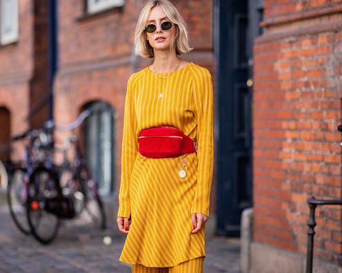 A woman in a yellow dress and an orange belt bag that is chic and convenient