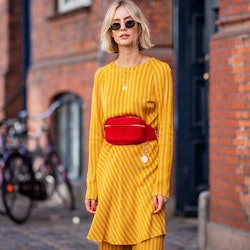 A woman in a yellow dress and an orange belt bag that is chic and convenient