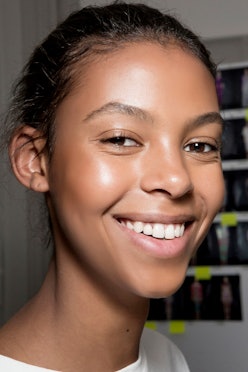 A young woman with a flawless, glowing skin smiling for a photo