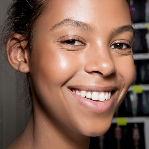 A young woman with a flawless, glowing skin smiling for a photo