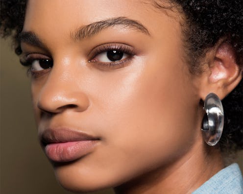 A model posing with non smudge mascara while wearing a silver earring