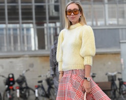 A blonde woman in a vanilla sweater, and a red-grey plaid skirt