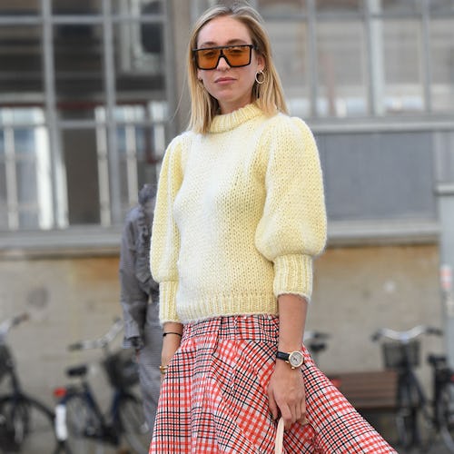 A blonde woman in a vanilla sweater, and a red-grey plaid skirt