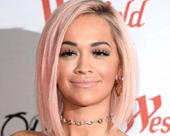 Rita Ora with a rose gold bob haircut, smiling while posing on a red carpet