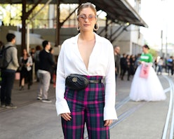 A woman wears pink-and-blue checkered pants, white shirt, and the micro bag around her waist paired ...