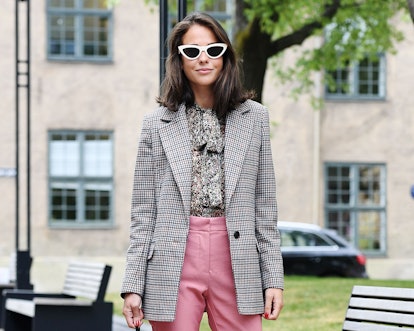 A woman posing in a silver cardigan and pink pants 