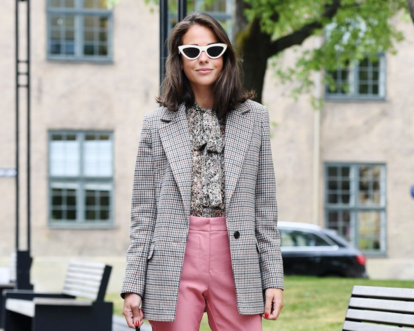 A woman posing in a silver cardigan and pink pants 